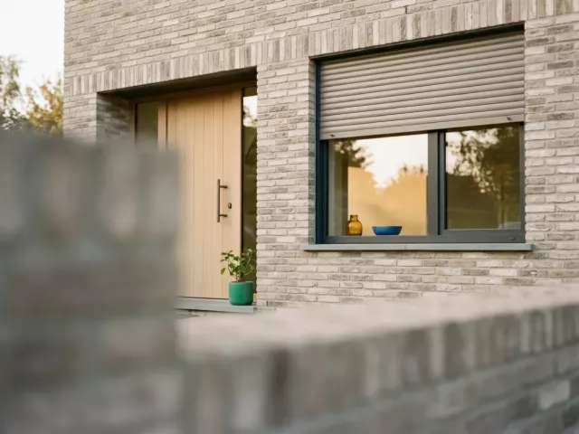 Fenêtre, porte d'entrée et volet extérieur sur une façade en briques